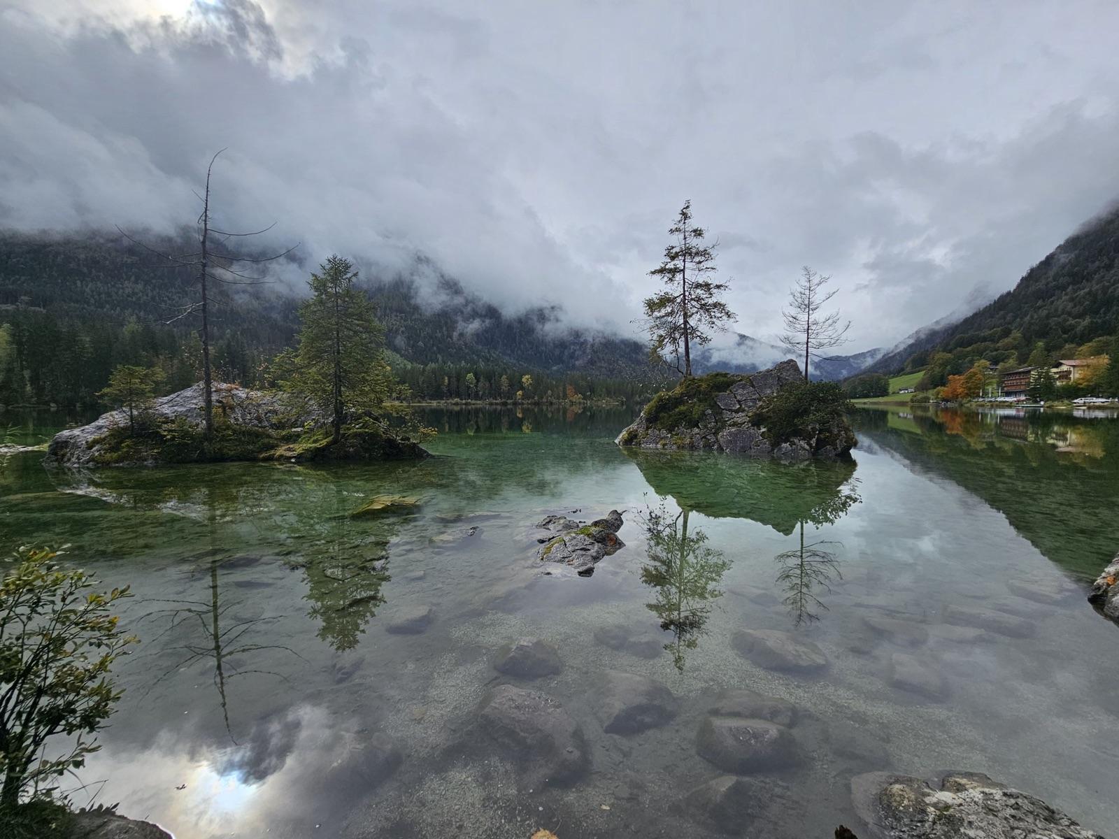 Tree-covered rocks reflected in the clear water of Hintersee in the Berchtesgaden Alps